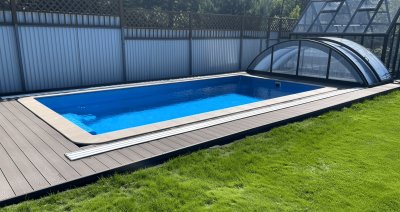 Прямоугольный бассейн с ярко-синей водой и террасной доской, сдвижной павильон